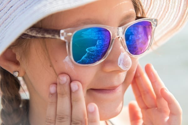 fille qui se met de la crème solaire